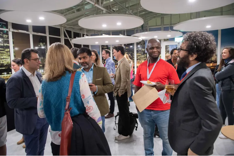 David Mensah, wearing an orange tee-shirt, talking with Dr Richard Brock at the MA in STEM Education Celebration event, 20 Nov 2021, King's College London.