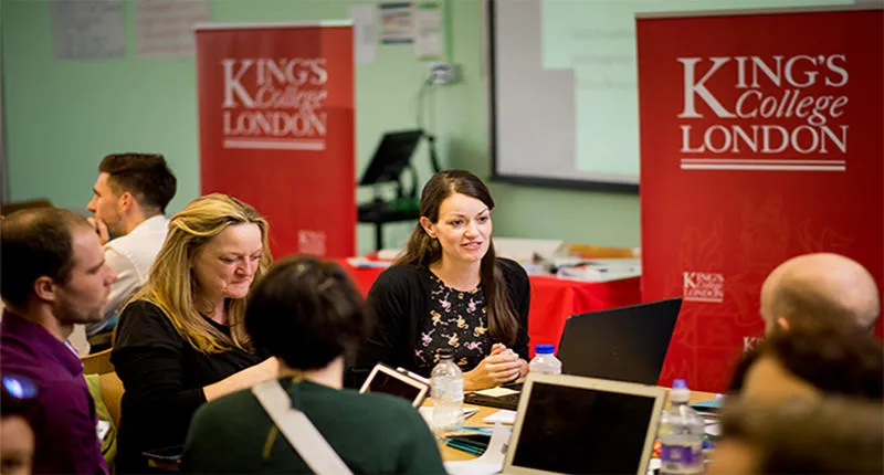 Students around a table with two red King's banners in the background