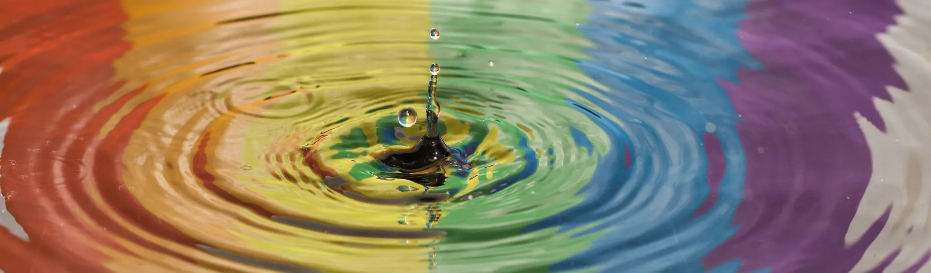 The colours of the LGBT flag (from left to right: red, orange, yellow, green, blue, purple and white) are showing over a pool of water.