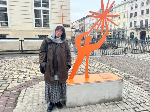 person stood next to orange cut out of person holding a star