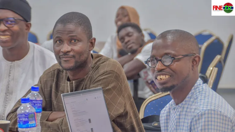two black african men sat at a conference with three people in the background looking engaged and happy