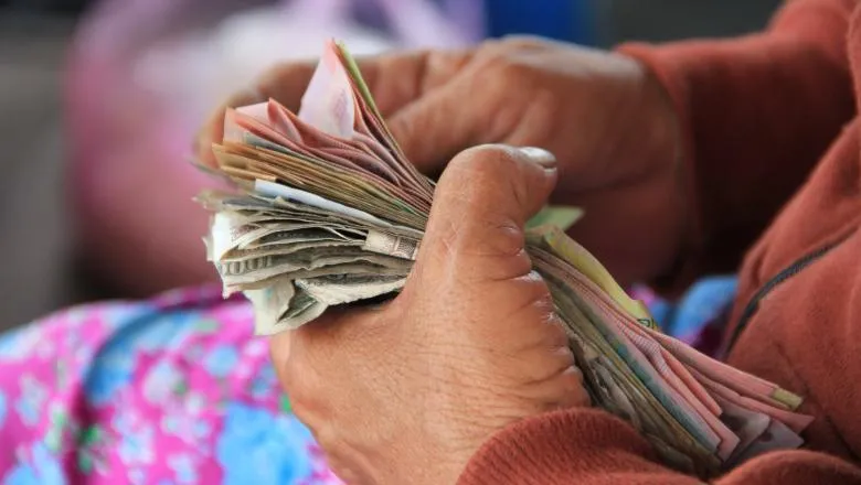 Photo of hands holding bills of different colours.