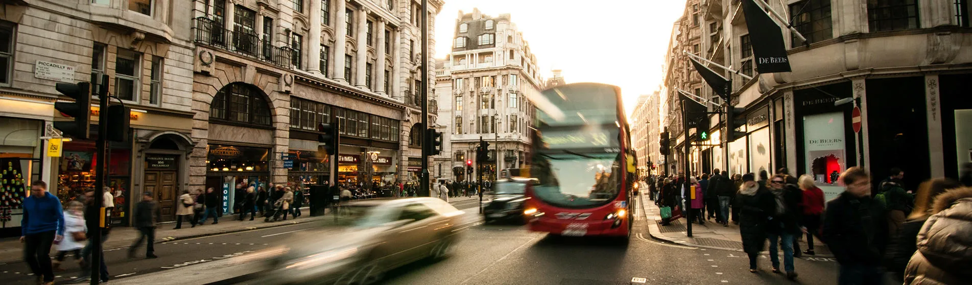 A street in London with people walking and a red bus