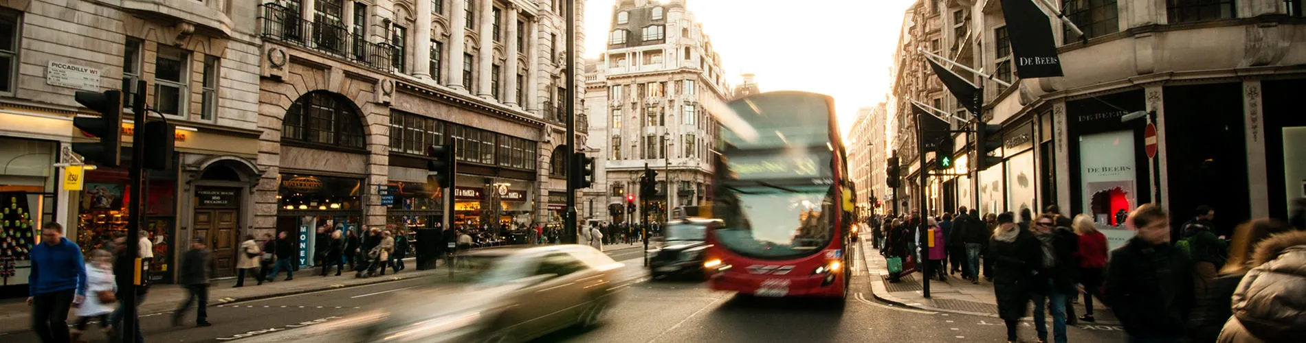 A street in London with people walking and a red bus
