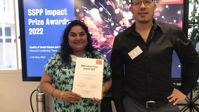 Chris Tang poses with Julie Begum in front of a screen for the SSPP Impact Prize Awards 2022