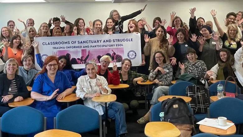 Teachers and students posing at the end of a class of English for speakers of other language, with a banner 'Classrooms of sanctuary and struggle'.