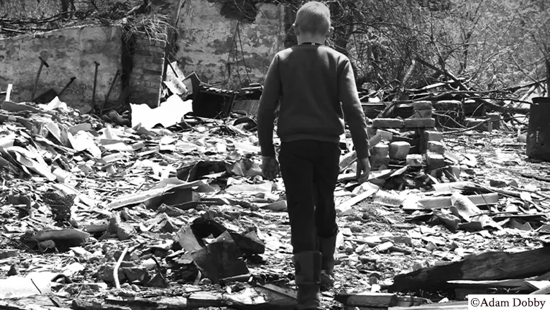 Image of a boy walking among a destroyed building in Ukraine