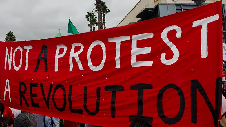 banner from public protest about Iran saying 'not a protest a revolution'