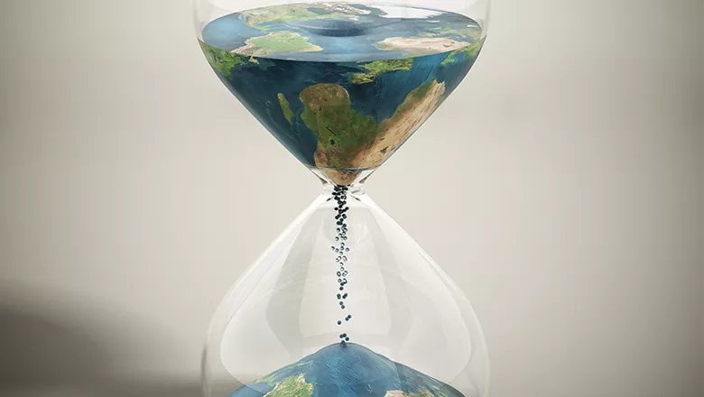 hourglass with sand running through that looks like planet earth