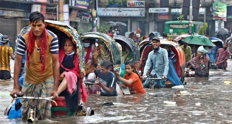 Vehicles try to drive through a flooded street in Dhaka, Bangladesh