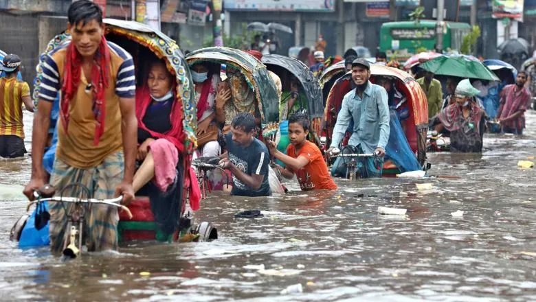 Vehicles try to drive through a flooded street in Dhaka, Bangladesh