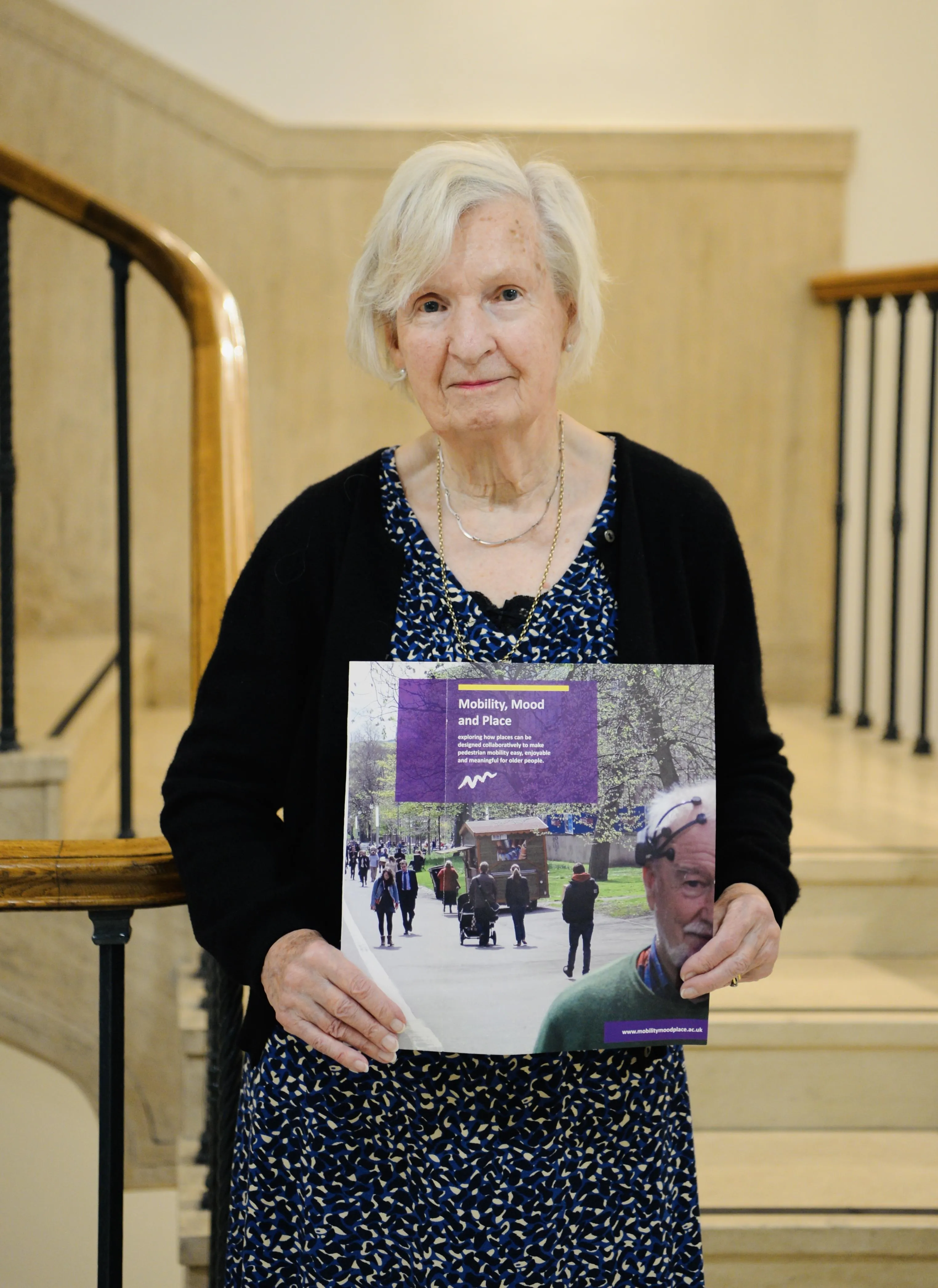 Anthea Tinker holding a copy of the Mobility, mood and place leaflet