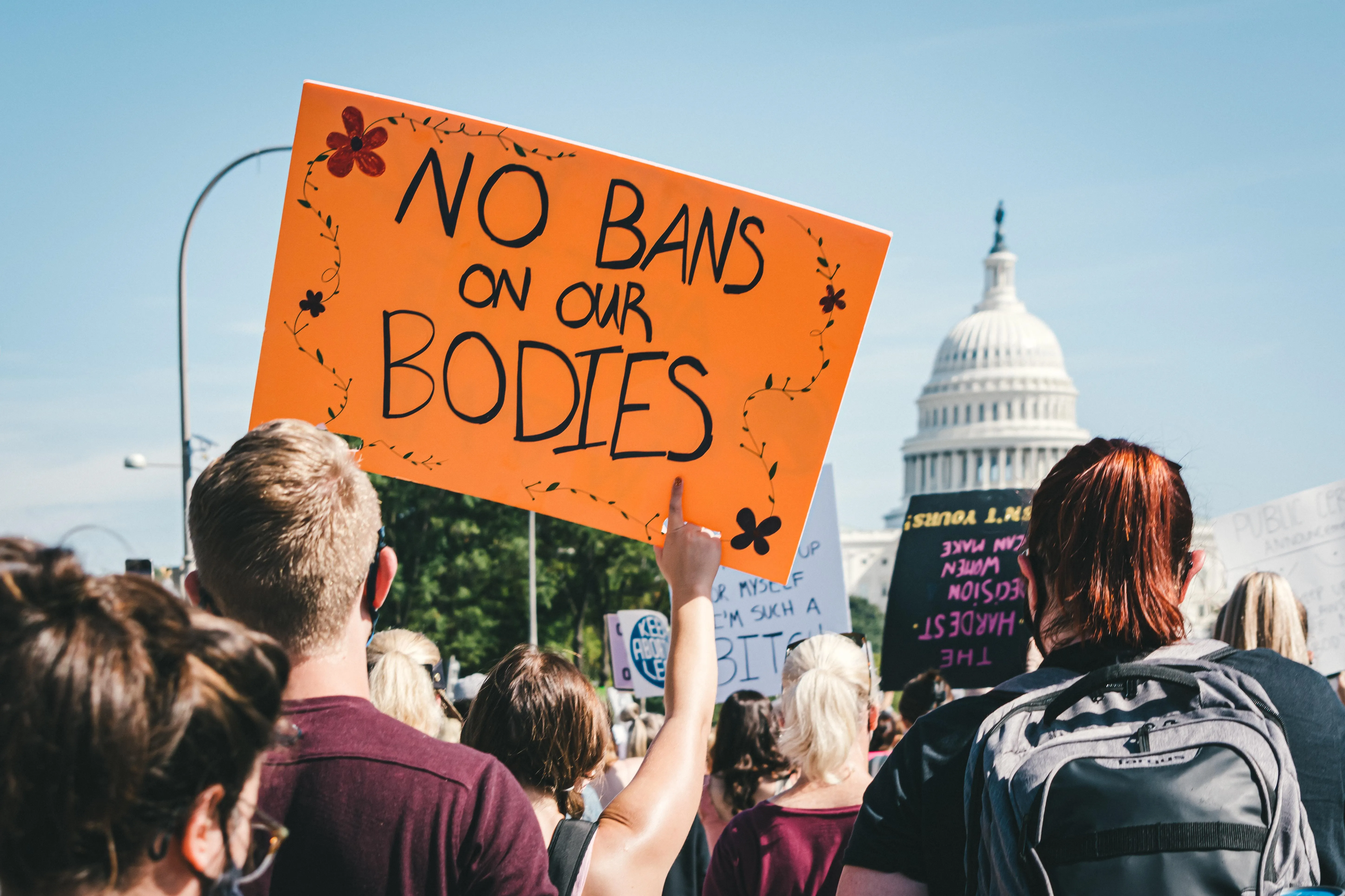 People protesting outside of Congress in Washington, D.C. An orange sign reads 