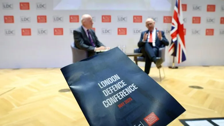 Conference programme held up in front of two seated people