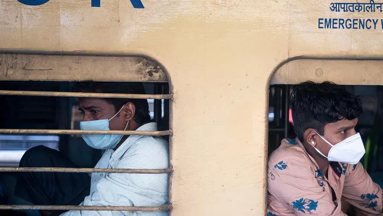 Two men wear face coverings while on emergency transport in India