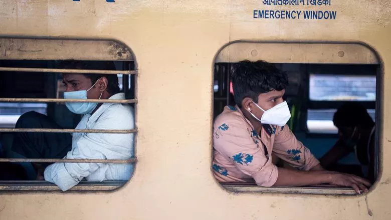 Two men wear face coverings while on emergency transport in India