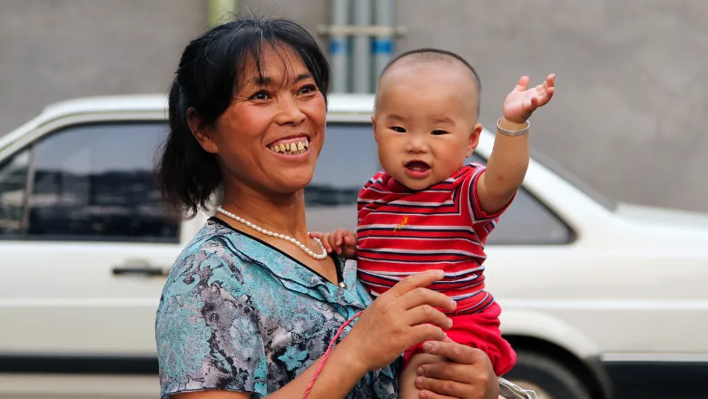 Smiling mother holding smiling baby who is waving