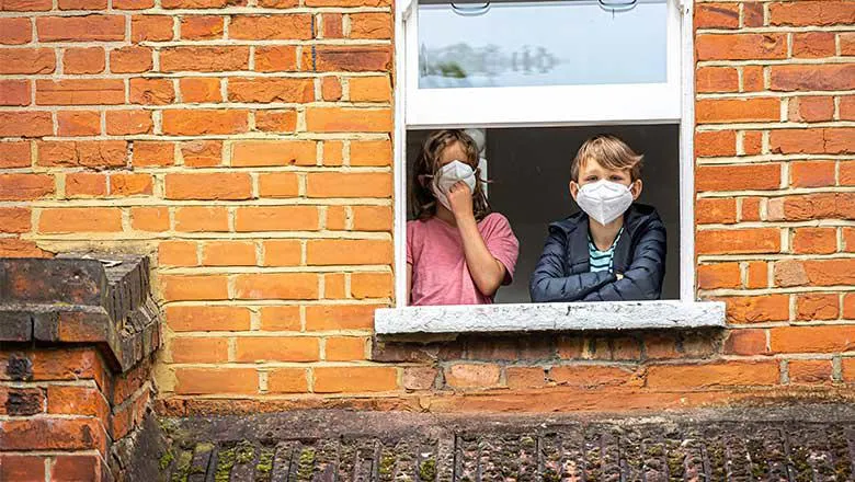 Kids wearing masks peering out the window