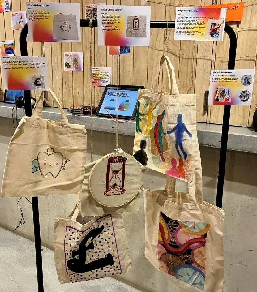 Tote bags with artwork on display at the exhibition. Images on the tote bags depict money, time cost and loneliness.