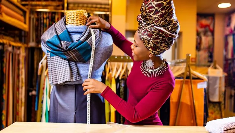 An African woman measuring clothes on a mannequin