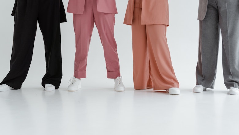 Four women wearing trousers and white trainers