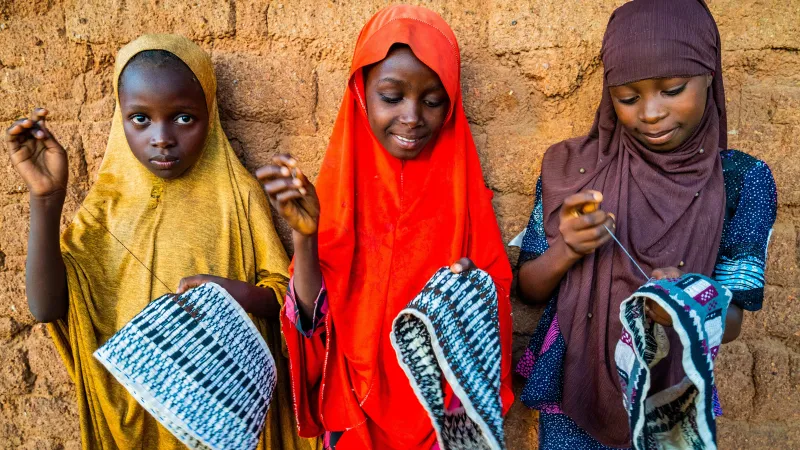 Three Nigerian girls sewing hats