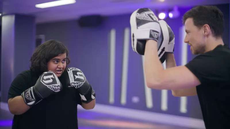 A student wearing box gloves sparring with a member of the King's Sport & Wellness team wearing pads