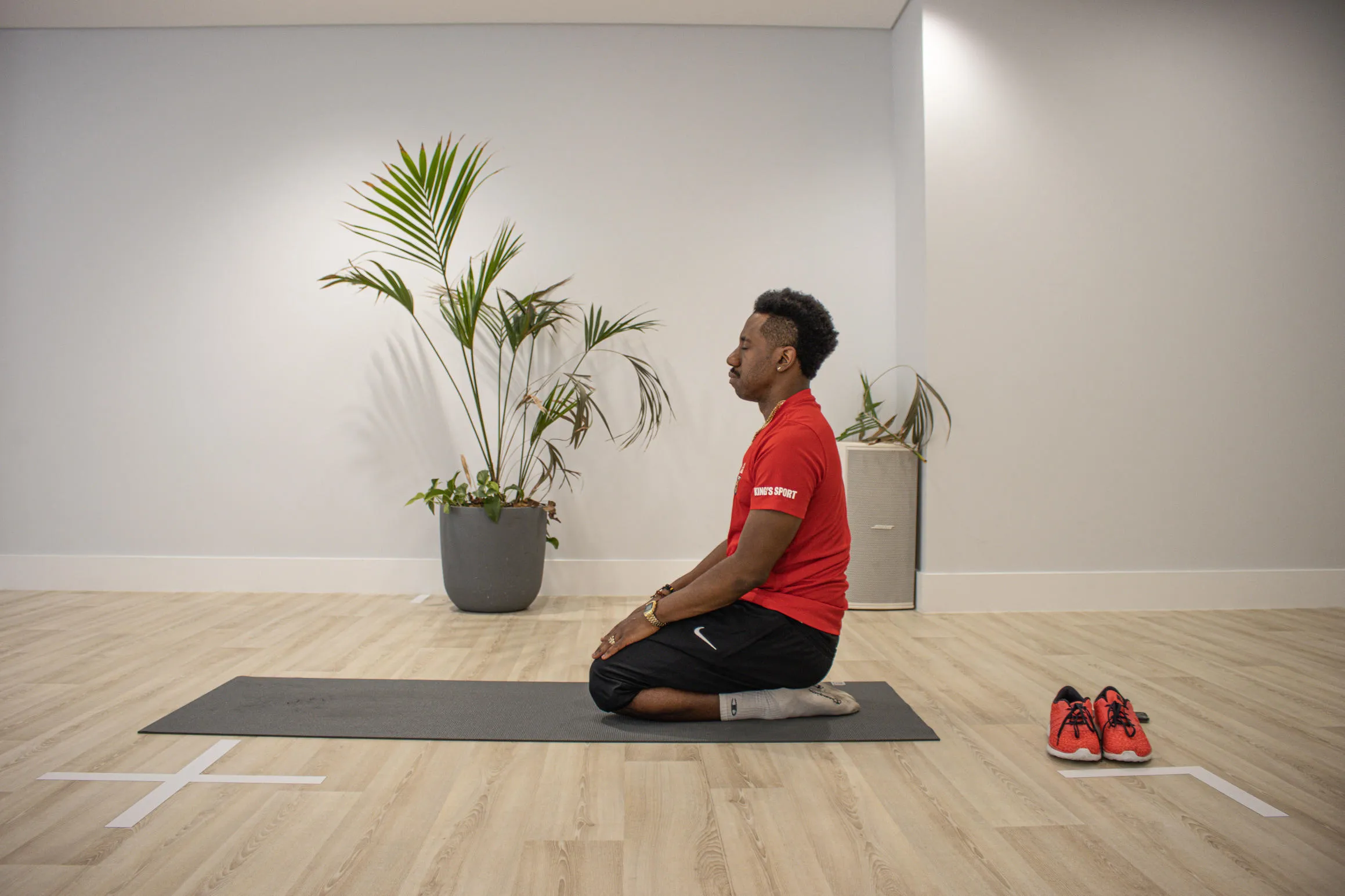 Personal trainer Arral Smith kneels on an exercise mat with his eyes closed