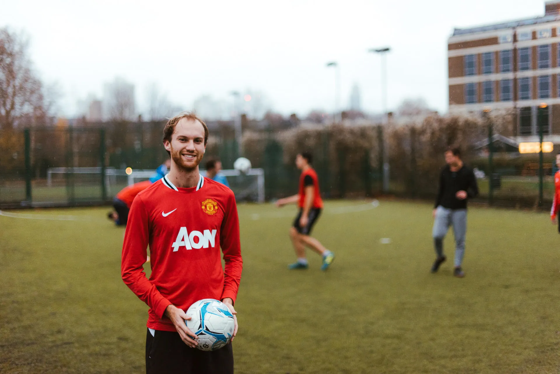 A smiling man in a park holding a football