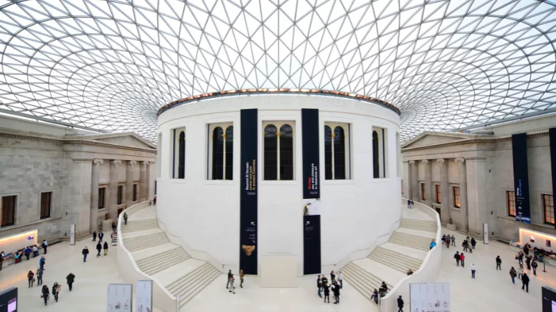 An image of the central hall of the british Museum, with the glass ceiling and staircase in the centre