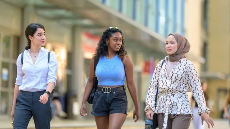 Three students walking and smiling outside a King's building
