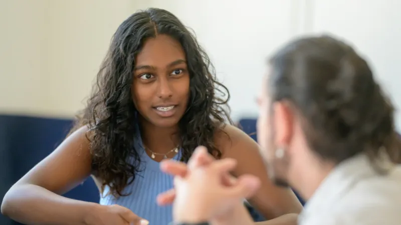 Two students sat at a table discussing.