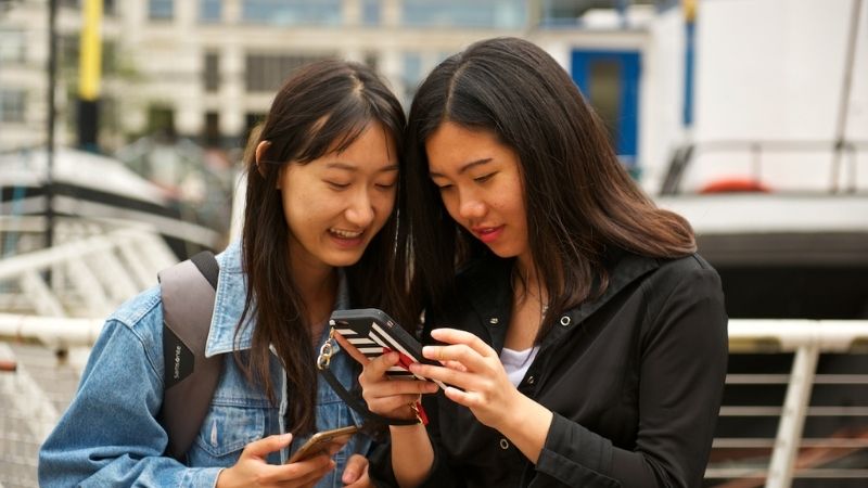 A photo of two students looking at a mobilephone