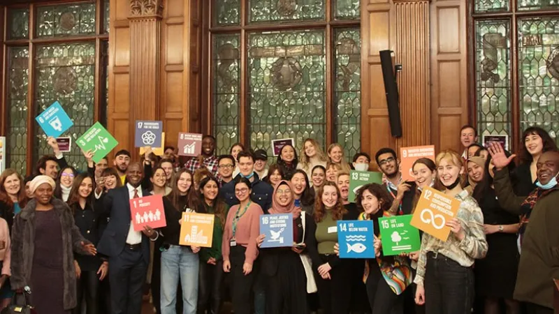 Sustainability group smiling at the camera holding up action signs