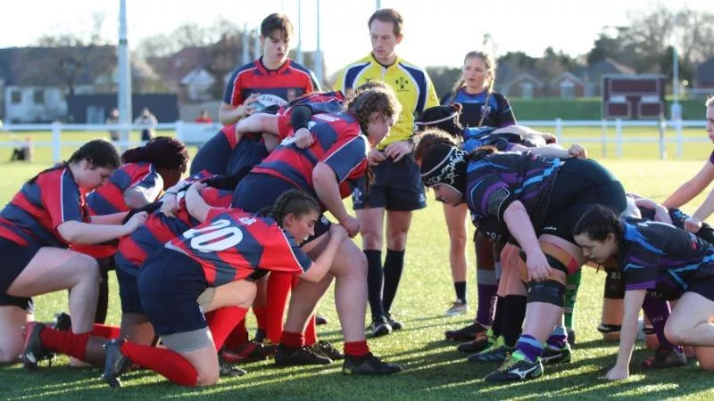 A rugby scrum about to take place, both teams are crouching