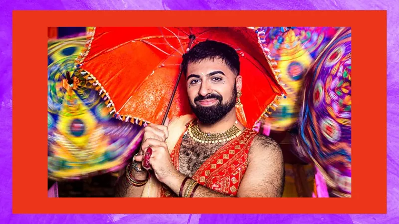 Vinay wearing an Indian vest and holding a red umbrella in front of a background of colourful umbrellas.