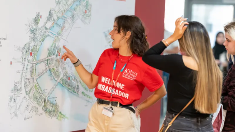 Welcome ambassador giving new students direction on a wall map