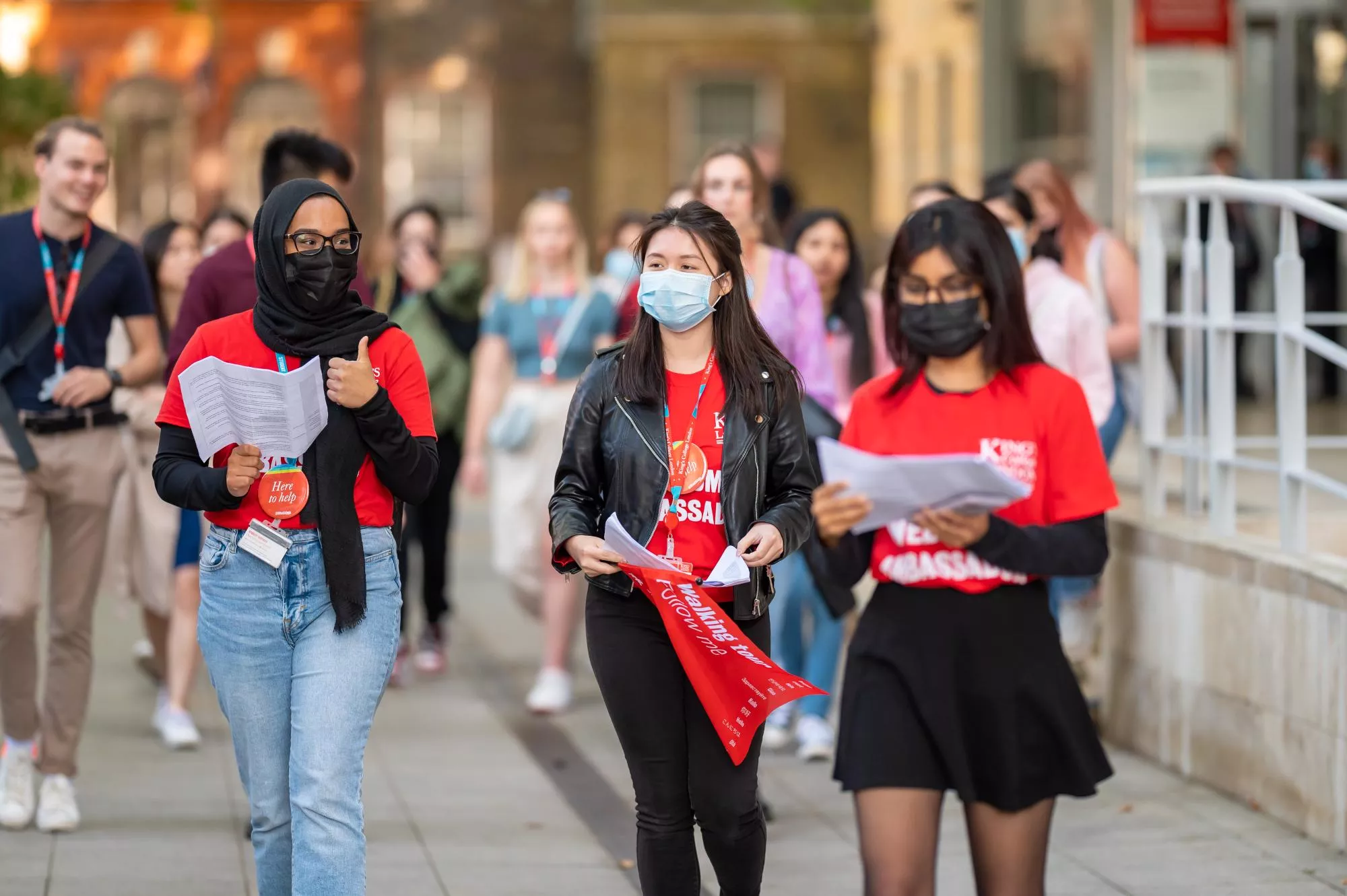 three student ambassadors wearing face coverings walk down the street