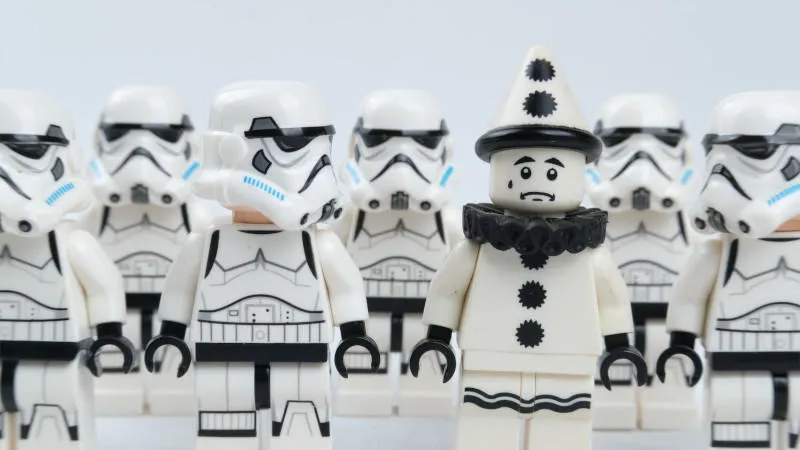 A group of Lego minifigures dressed as Stormtroopers. One looks to its left at another minifugure conspicuously dressed as a clown