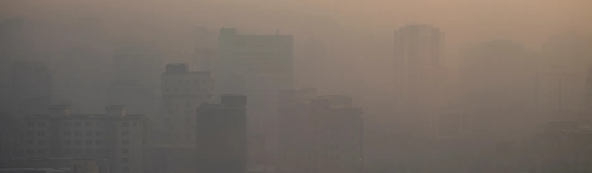 A city skyline seen through thick smog at sunset