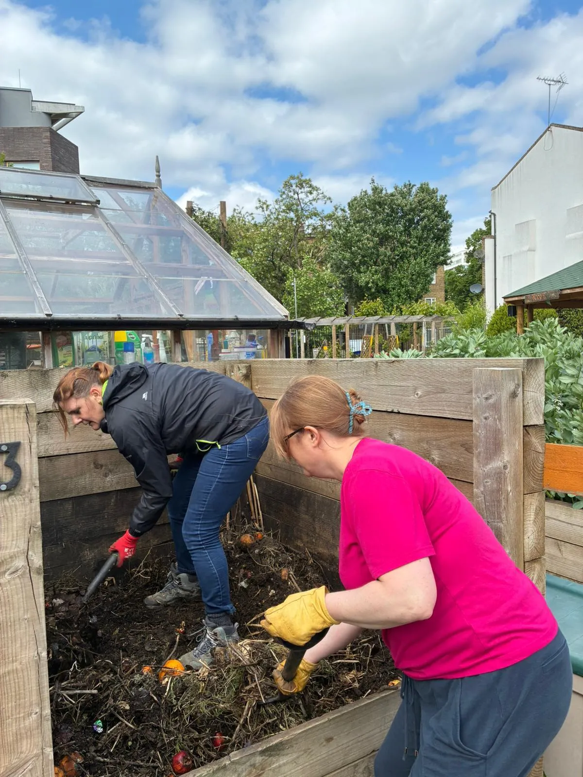 Two women filling a composting bin