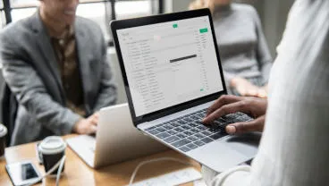 Person holding a laptop in a meeting