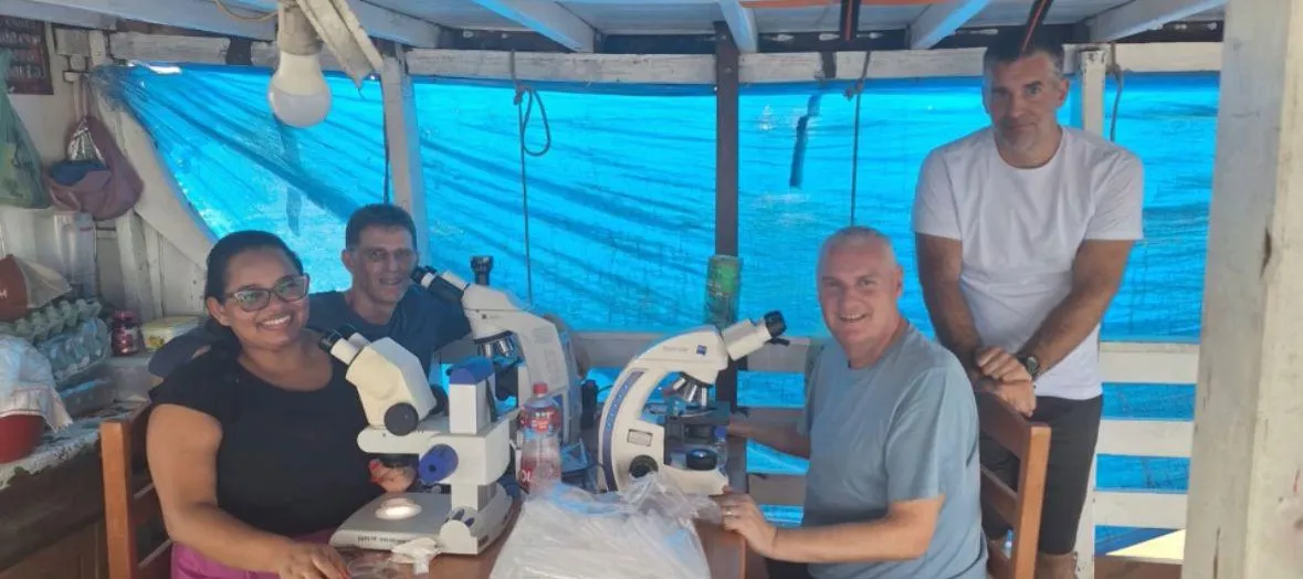 Four scientists looking at microscopes on a boat