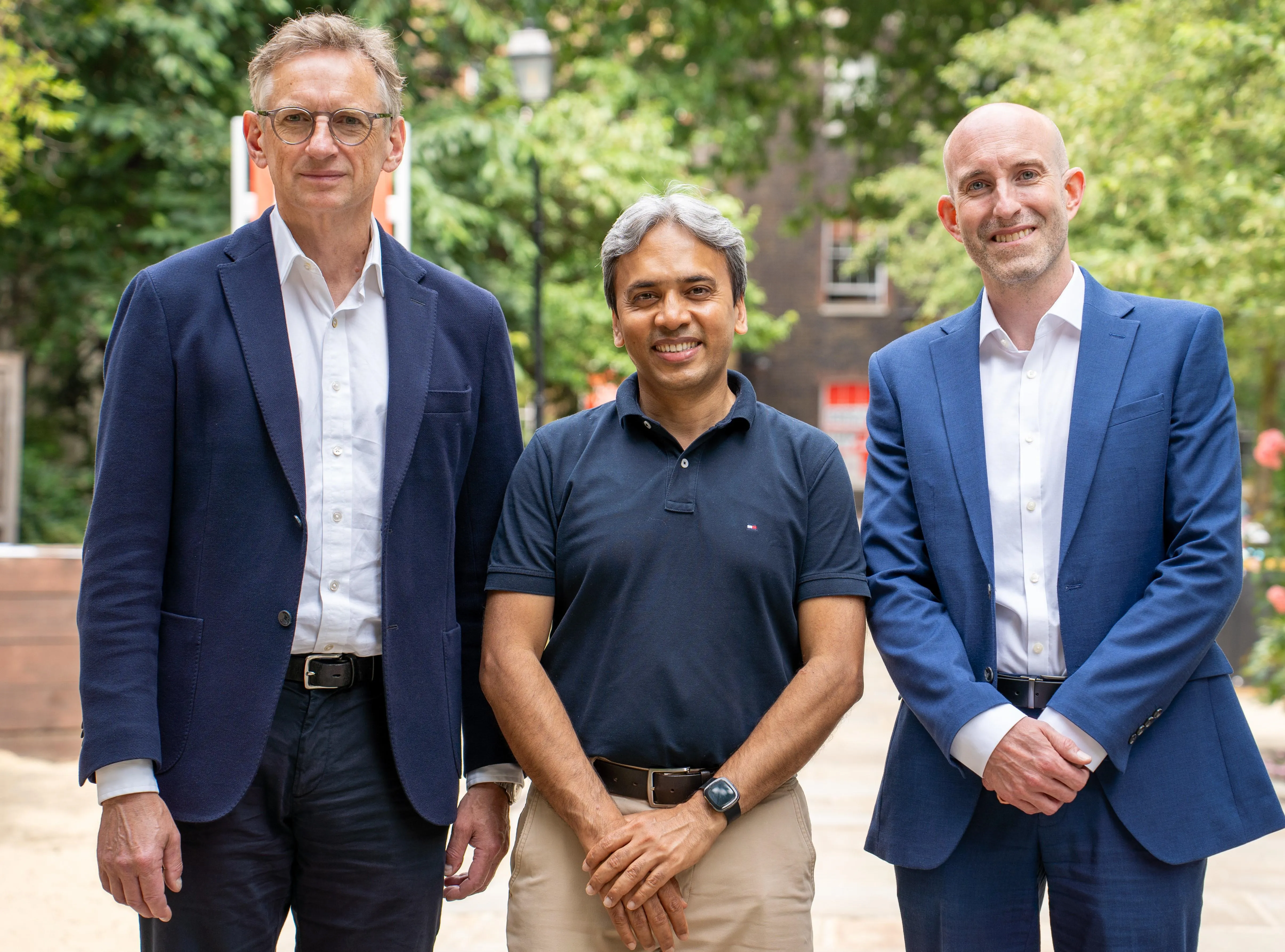 Three people smiling in front of leafy background