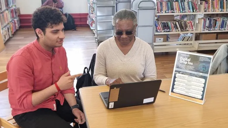 Aditya Dixit sits next to a woman in a library who is typing on a laptop 