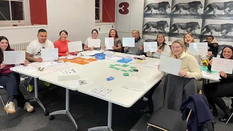 Ten people sit round a table holding up signs