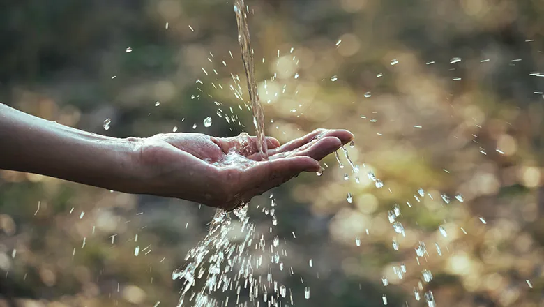 A hand being held out with water splashing onto it